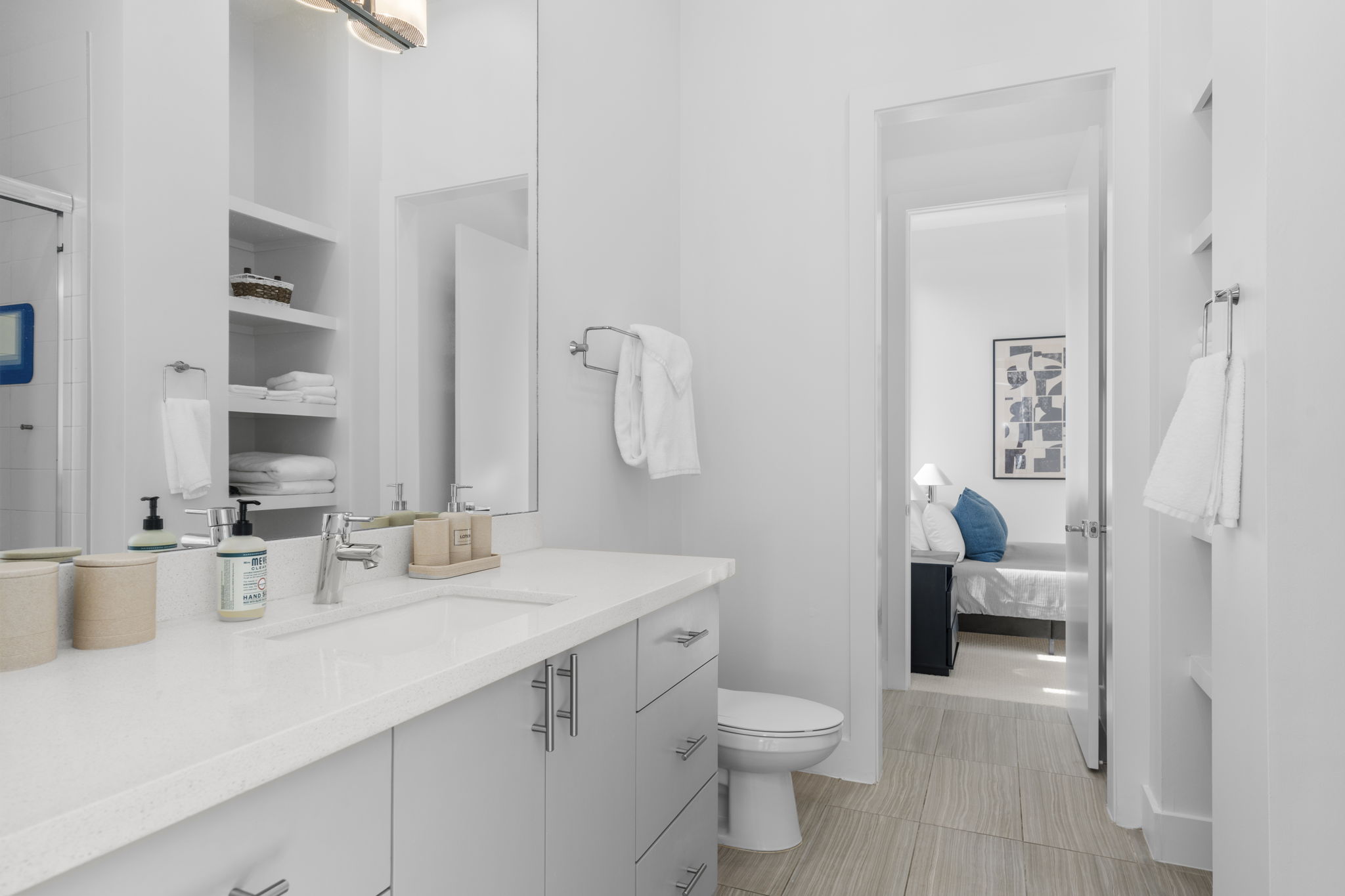Bathroom vanity with open shelving looking into a bedroom